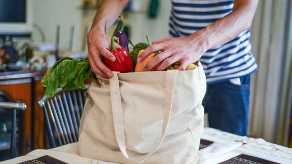 A person puts vegetables into a bag.
