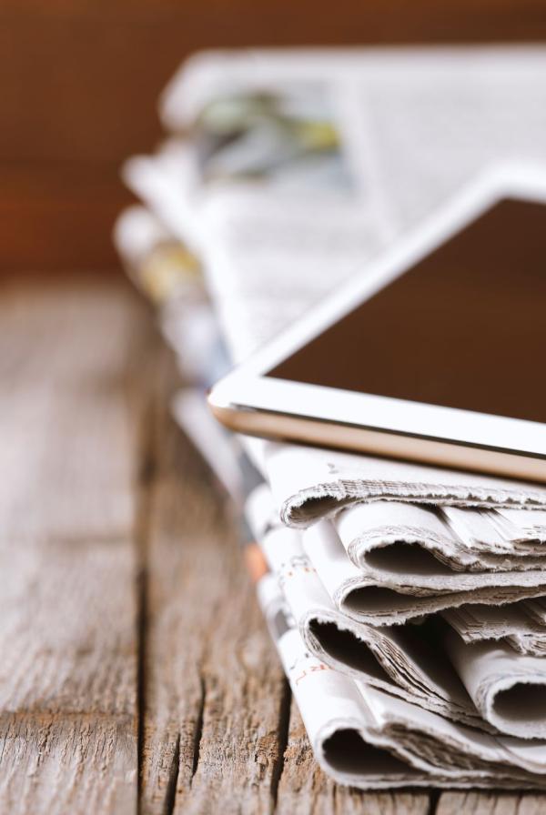 Stack of newspapers weighed down by a tablet