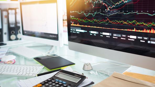 A screen with graphs, and a calculator on a desk.