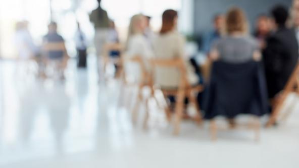 People seated listening to a presentation, slightly blurred