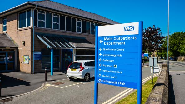 An NHS outpatients sign outside of a hospital.