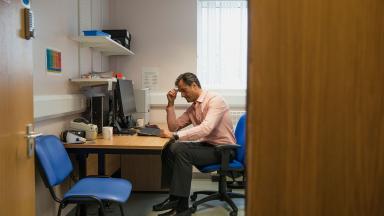 A general practitioner thinking in his consultation room.