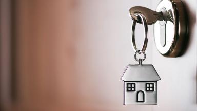 A key in a door with a house-shaped keyring. 