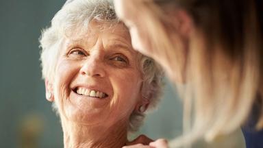 An older woman smiles at her carer.