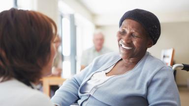 A wheelchair user talking to a healthcare assistant.