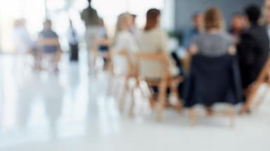 People seated listening to a presentation, slightly blurred