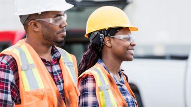 Two maintenance workers in hard hats and high visibility jackets.