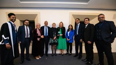 10 formally dressed award recipients stand in a row facing the camera and smiling