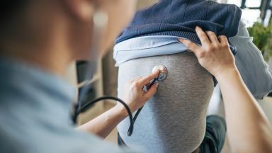 Doctor examining man's lungs with stethoscope 