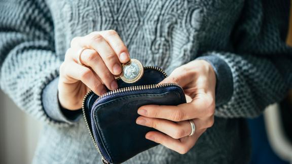 A two pound coin being put into a purse.