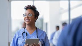 A smiling doctor holding a tablet computer.