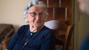 An elderly patient sitting in a wooden chair.