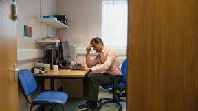 A general practitioner thinking in his consultation room.