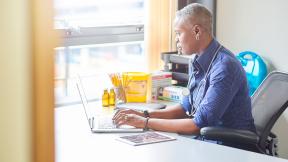 A general practitioner, typing, near a window.