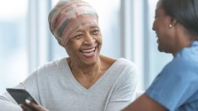 A patient and carer, laughing and looking at a tablet.