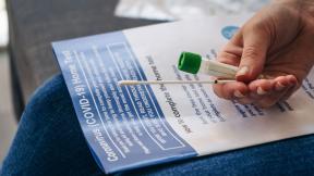 A person holds a COVID-19 testing kit.