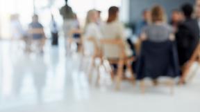 People seated listening to a presentation, slightly blurred