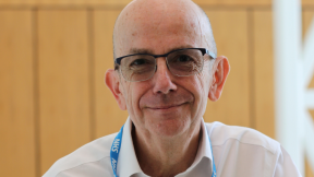 Image of Simon Weldon smiling and wearing glasses, a white shirt and an NHS lanyard