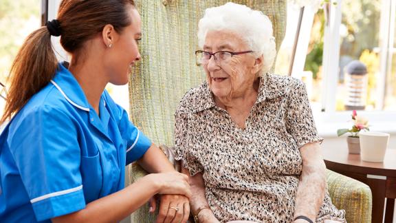 A nurse talking to a an elderly patient in a care home.
