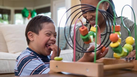 Child and therapist playing with a toy and laughing.