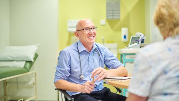 A doctor on a ward, consulting a patient.