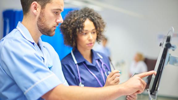 Healthcare workers checking a monitor on a ward.