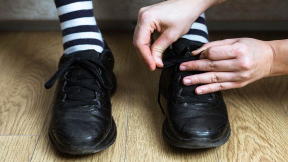 A person helps to tie someone else's shoes.