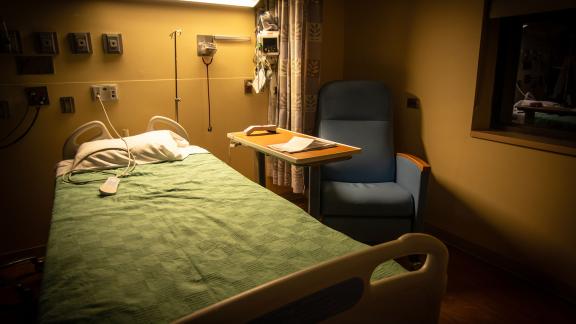 An empty hospital bed, on a ward at night time.