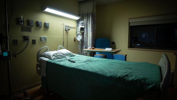 An empty hospital bed, on a ward at night time.