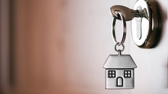 A key in a door with a house-shaped keyring. 