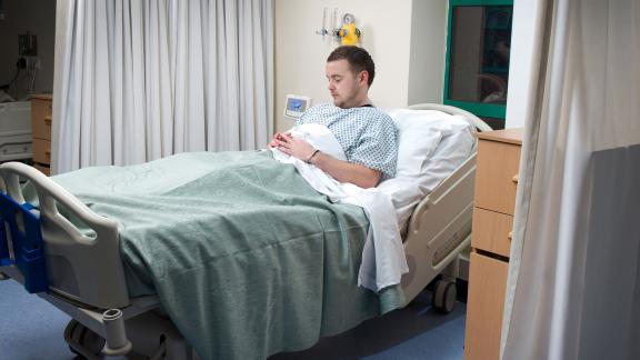 A male patient sitting up in a hospital bed.