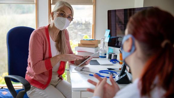 Masked GP talking to patient