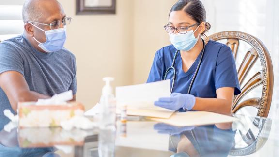 A doctor on a home visit, consulting a patient.