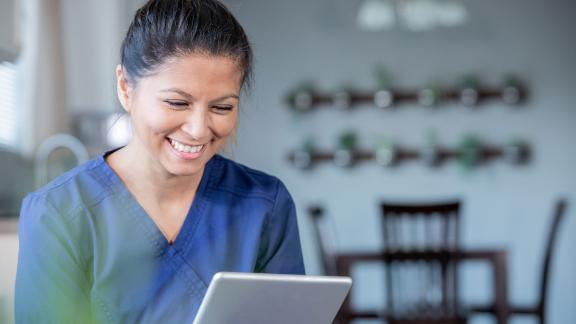 A nurse smiling at a tablet.