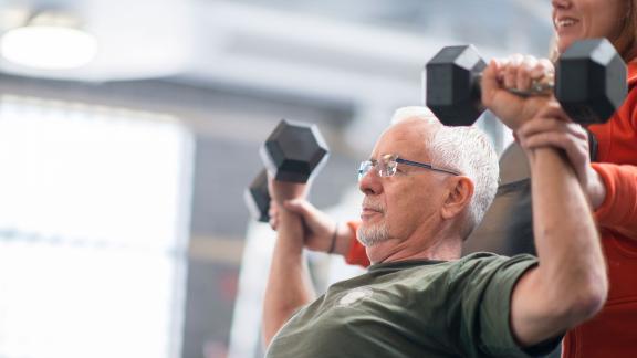 An older man lifting dumbbells.