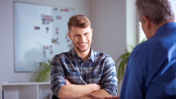 Two men talking, one is smiling. 