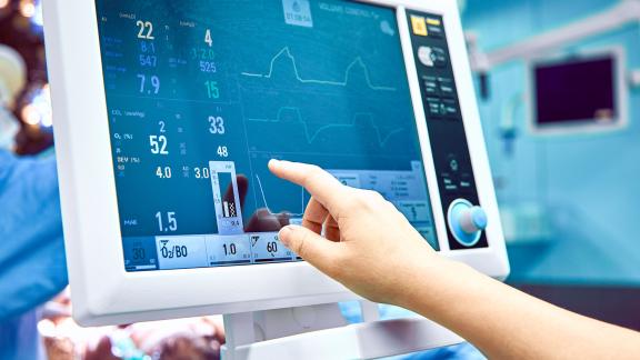 A hospital worker pointing to a monitor.