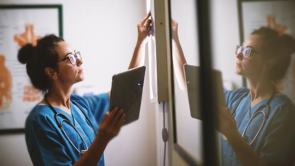 A radiographer holding a tablet, looking at a scan.