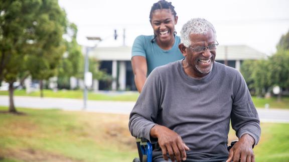 A man in wheelchair and his carer, laughing.