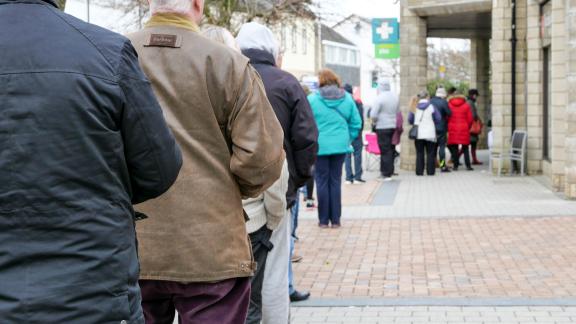 Customers waiting in a distanced queue for a pharmacy.