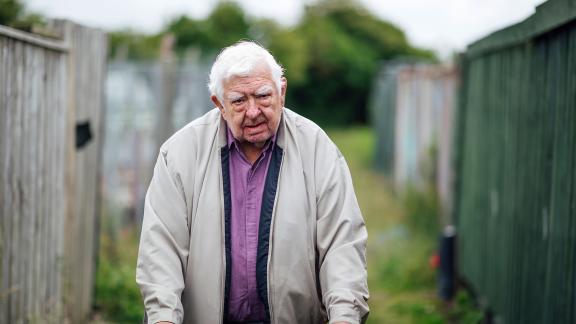 An elderly man standing in an allotment.