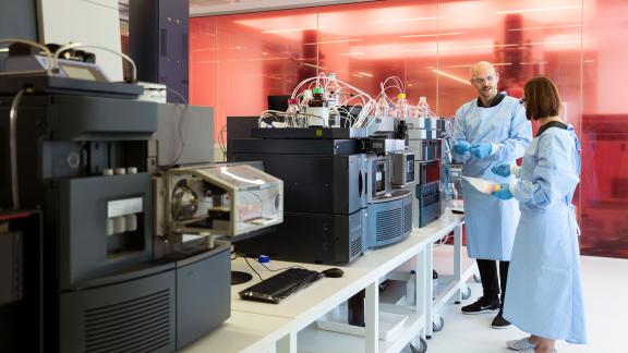 Healthcare scientists engaged in conversation, next to a machine.