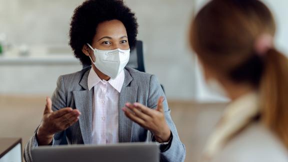 A masked doctor consulting a patient.