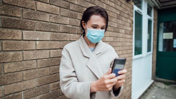 A masked patient outside a doctors' surgery.
