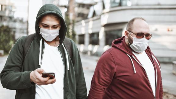 Two men holding hands wearing face masks