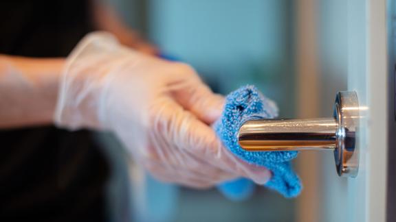 A gloved hand wiping a door handle.