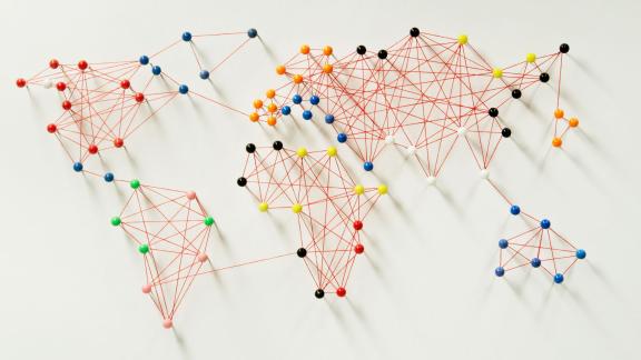 Multicoloured pins and string which connect up to form world map