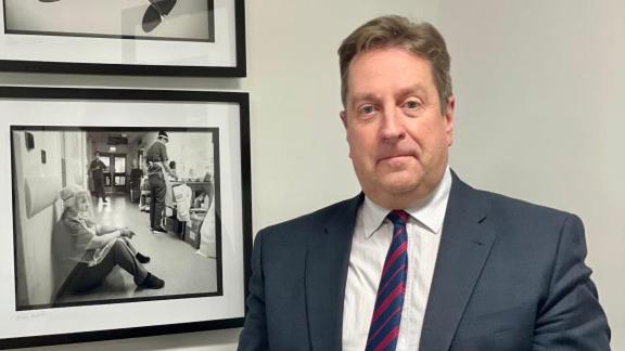 Jonathan Patton, Vice Chair, NICON, stood beside two wall-mounted black and white photographs