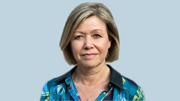 Julie Bass stood posing in front of a light blue background.