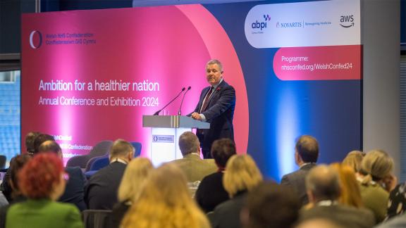 Jeremy Miles speaking in front of a seated crowd at the Welsh NHS Confederation Conference 2024.
